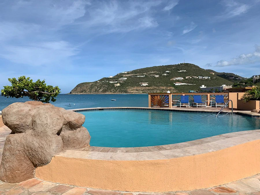 Infinity-edge swimming pool at Divi Little Bay Beach Resort with a rock waterfall feature and panoramic views of the ocean and mountains.

How does Divi Resorts timeshare work?