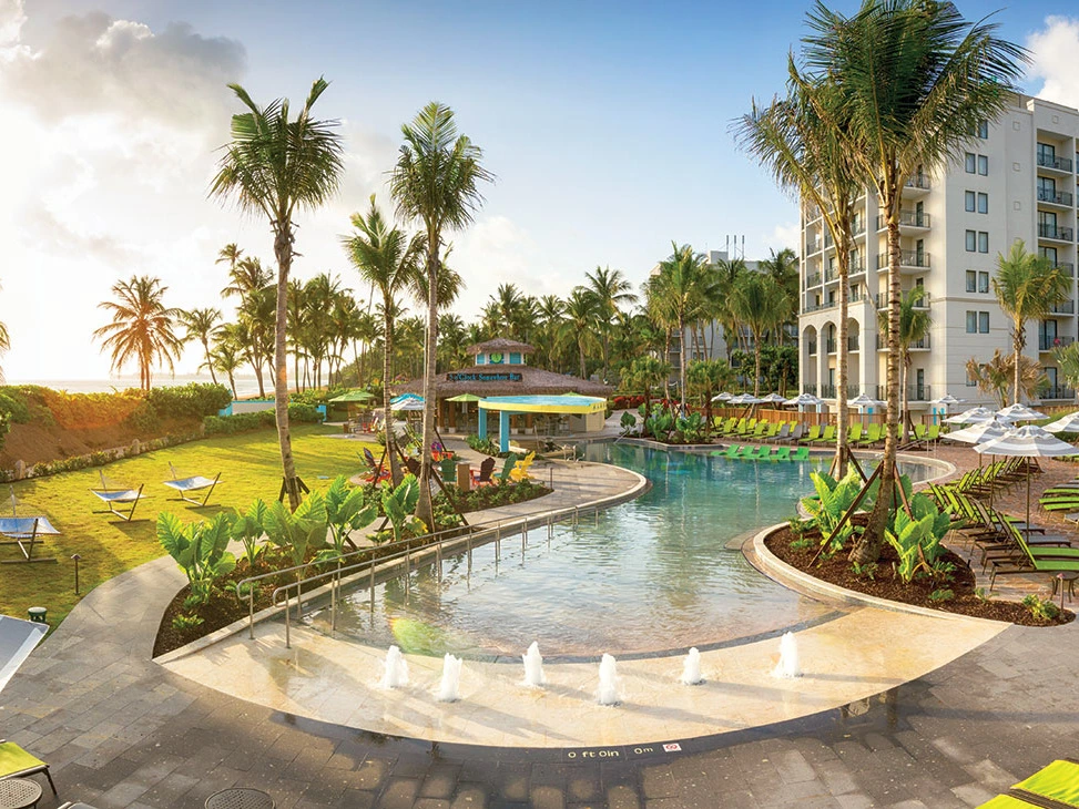 Tropical pool area at Margaritaville Vacation Club at Wyndham Rio Mar featuring the 5 O'Clock Somewhere Bar and ocean views.