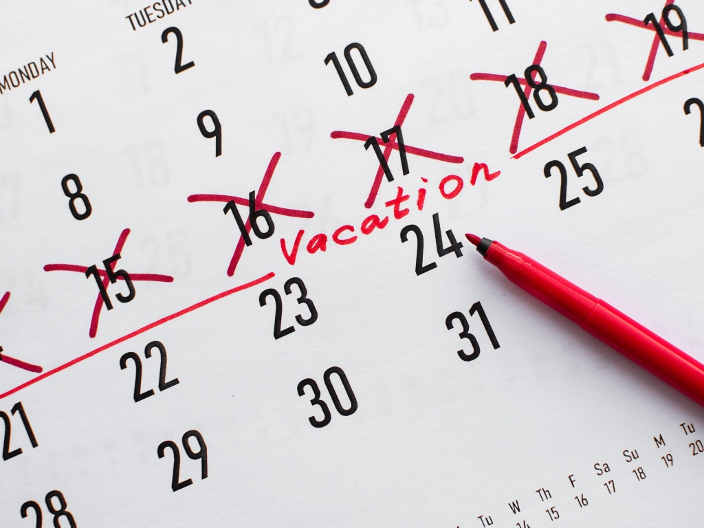 Close-up of a calendar with dates crossed out in red marker leading up to the handwritten word Vacation.
