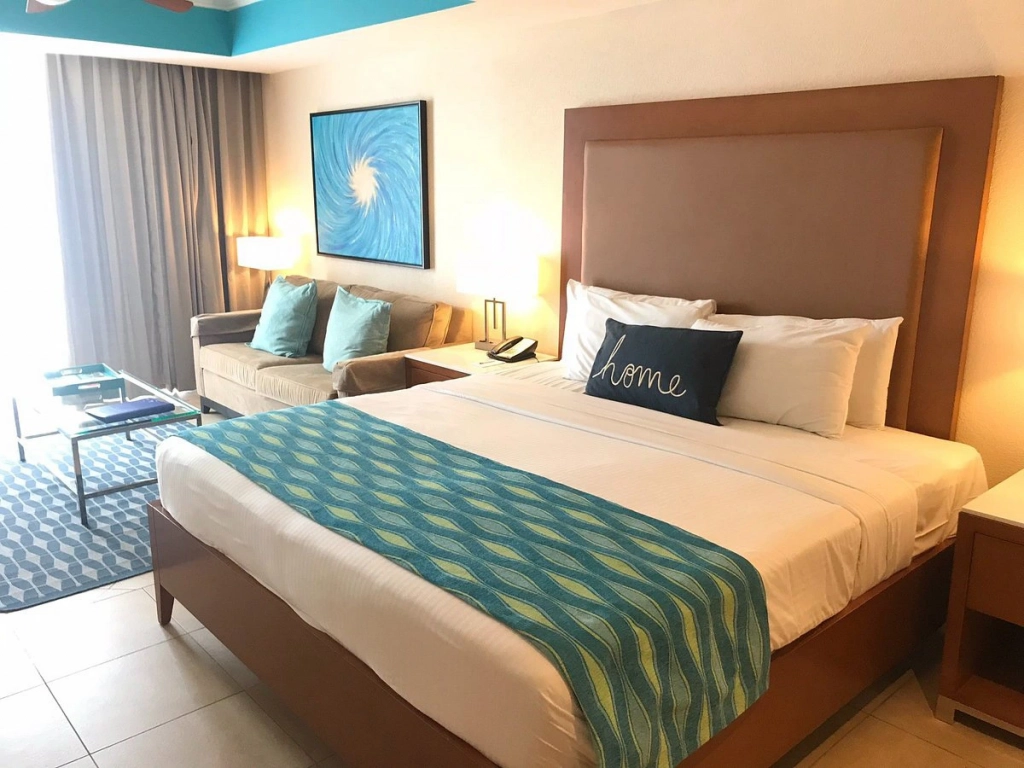 Modern studio suite interior at Divi Aruba Phoenix Beach Resort featuring a king-size bed with teal accents, a sofa bed, and coastal-themed wall art.

How does Divi Resorts timeshare work?