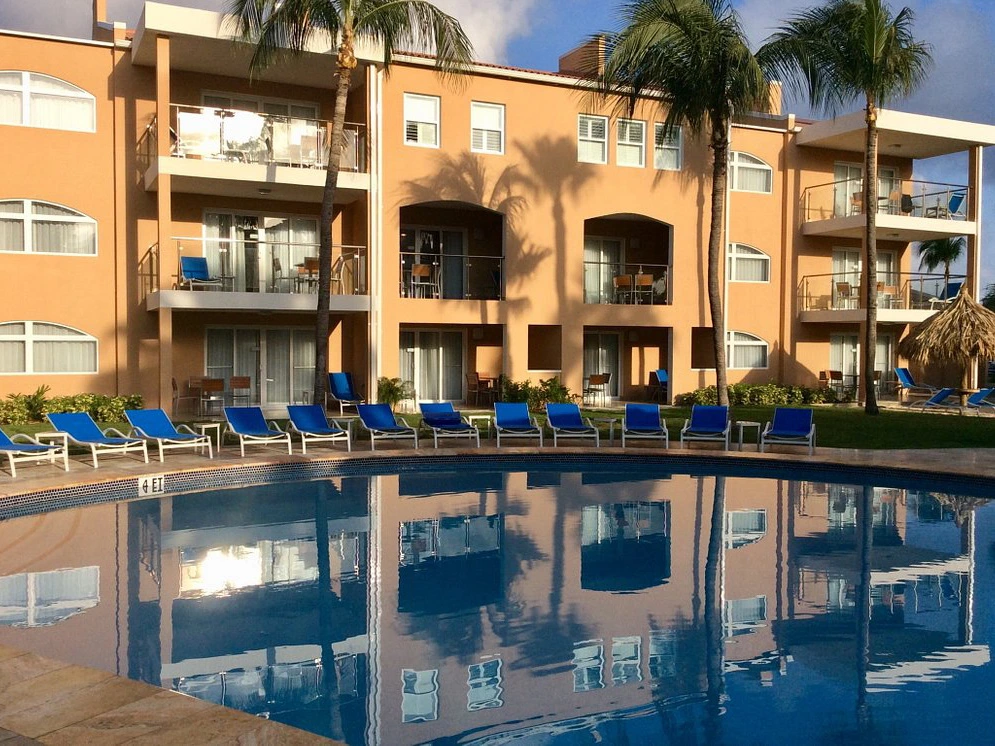 Sparkling swimming pool reflecting a peach-colored resort building and palm trees at Divi Dutch Village Beach Resort in Aruba.

How does Divi Resorts timeshare work?