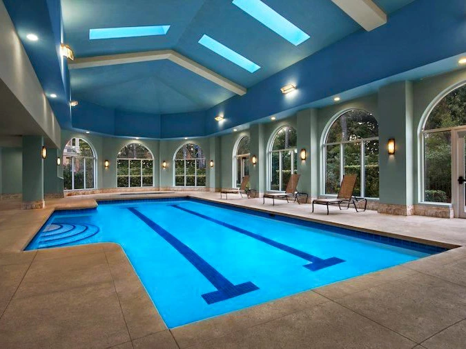 Indoor swimming pool at Marriott's Oceanwatch with blue water and lounge chairs by large windows.