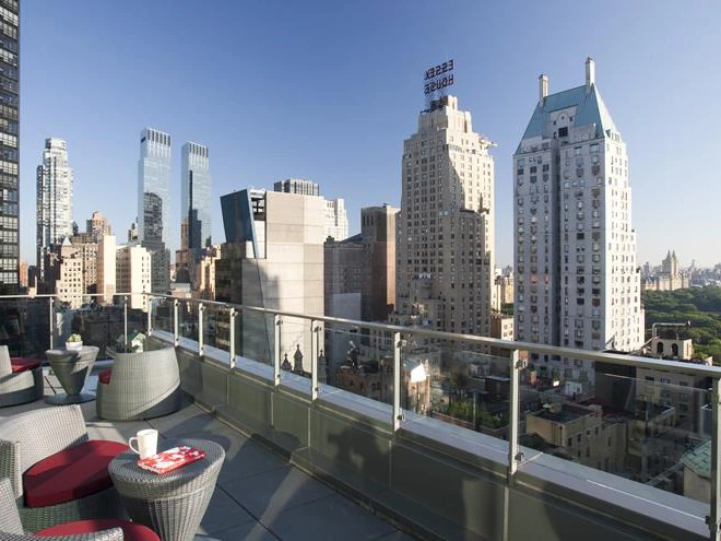 Spacious glass-paneled balcony at West 57th Street by Hilton Club featuring lounge seating and panoramic views of the New York City skyline.