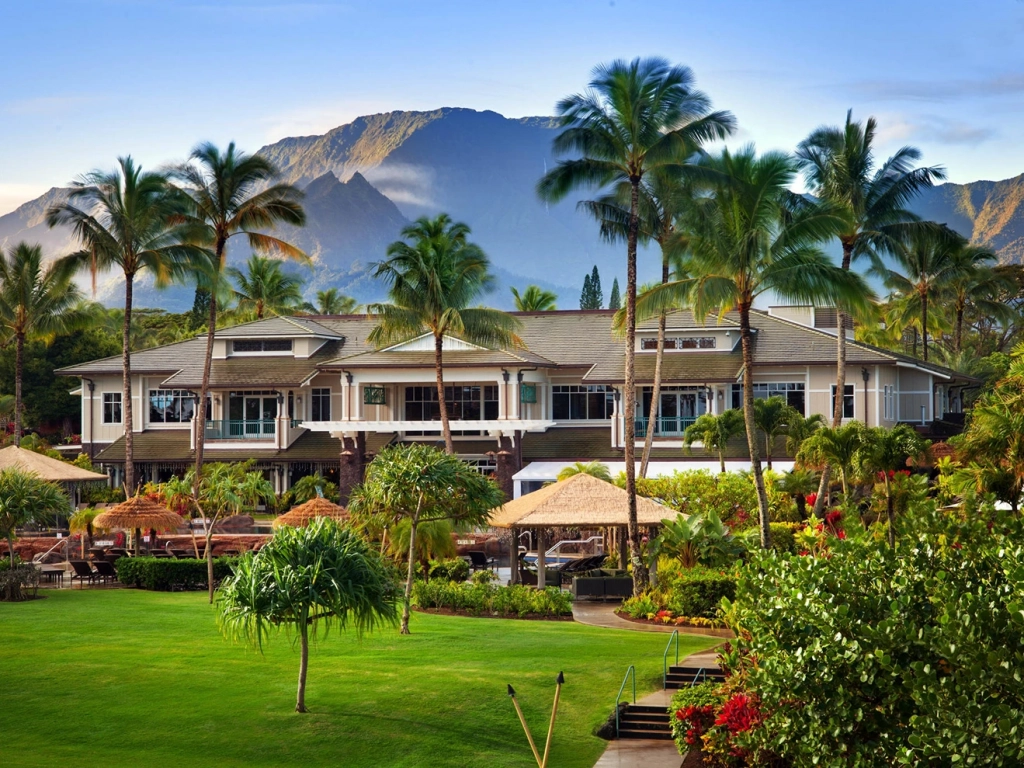 Scenic exterior of The Westin Princeville Ocean Resort Villas surrounded by towering palm trees, manicured lawns, and majestic mountains. Difference Between Points and Weeks Timeshare