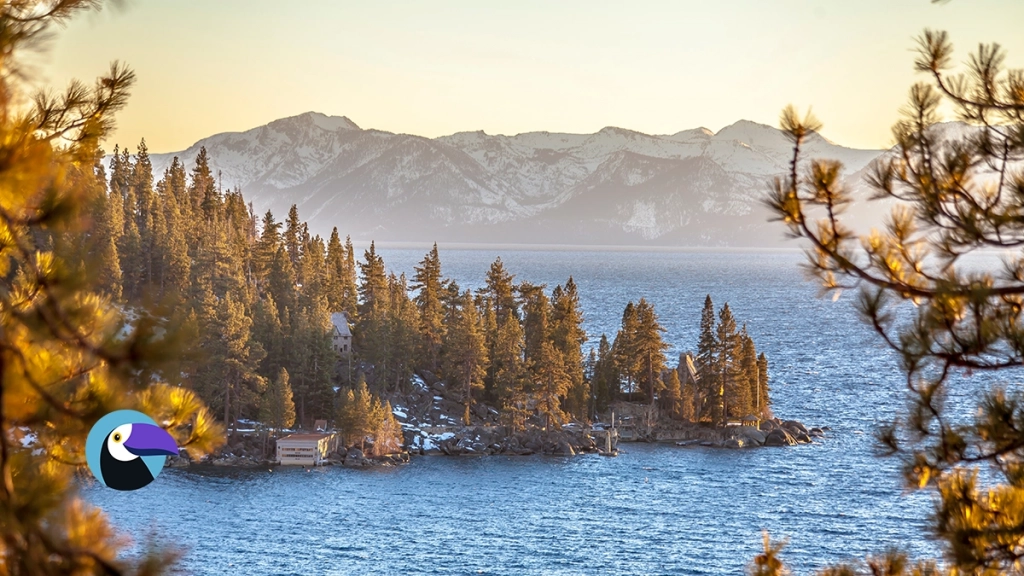 Scenic golden hour view of Lake Tahoe's blue water and snow-capped Sierra Nevada mountains.