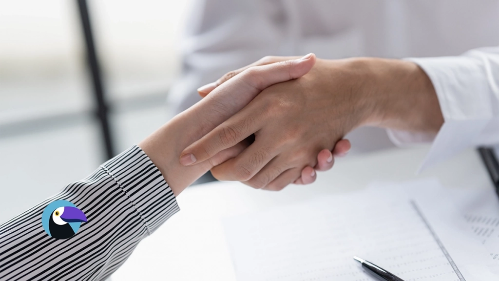 Two people shaking hands over a desk with paperwork, symbolizing a right of first refusal agreement.