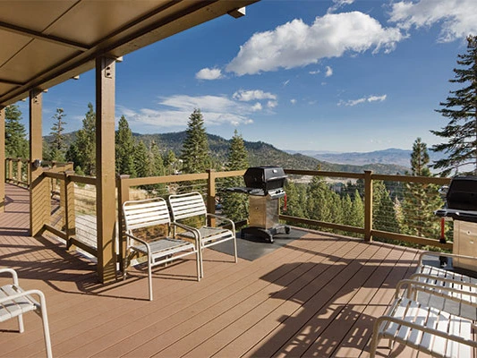 Spacious wood deck with outdoor grills and seating overlooking the mountains at a Lake Tahoe timeshare.