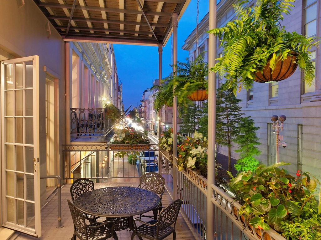 Wrought iron patio seating on a balcony overlooking Decatur Street at Club La Pension in New Orleans.