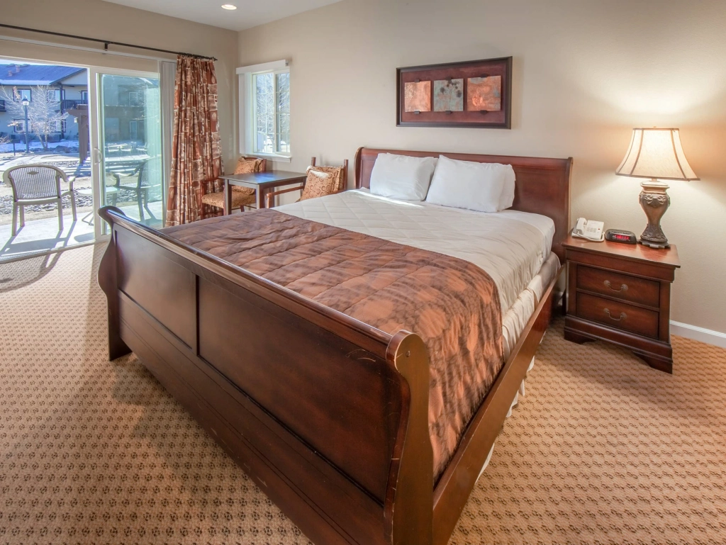 Traditional resort bedroom with a dark wood sleigh bed and sliding glass door to a private patio.