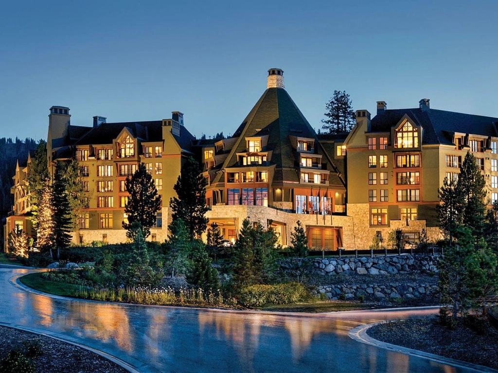 Illuminated evening exterior of a grand stone and wood Lake Tahoe timeshare resort.