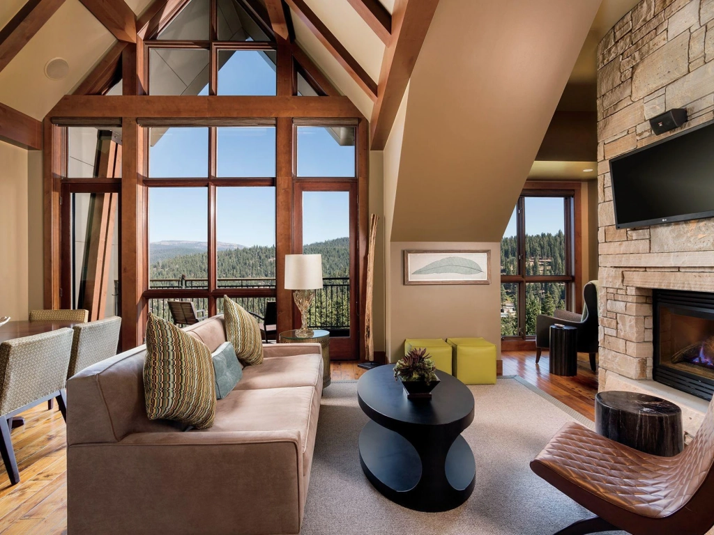 High-ceiling living room with floor-to-ceiling windows overlooking a forest at a Lake Tahoe timeshare.