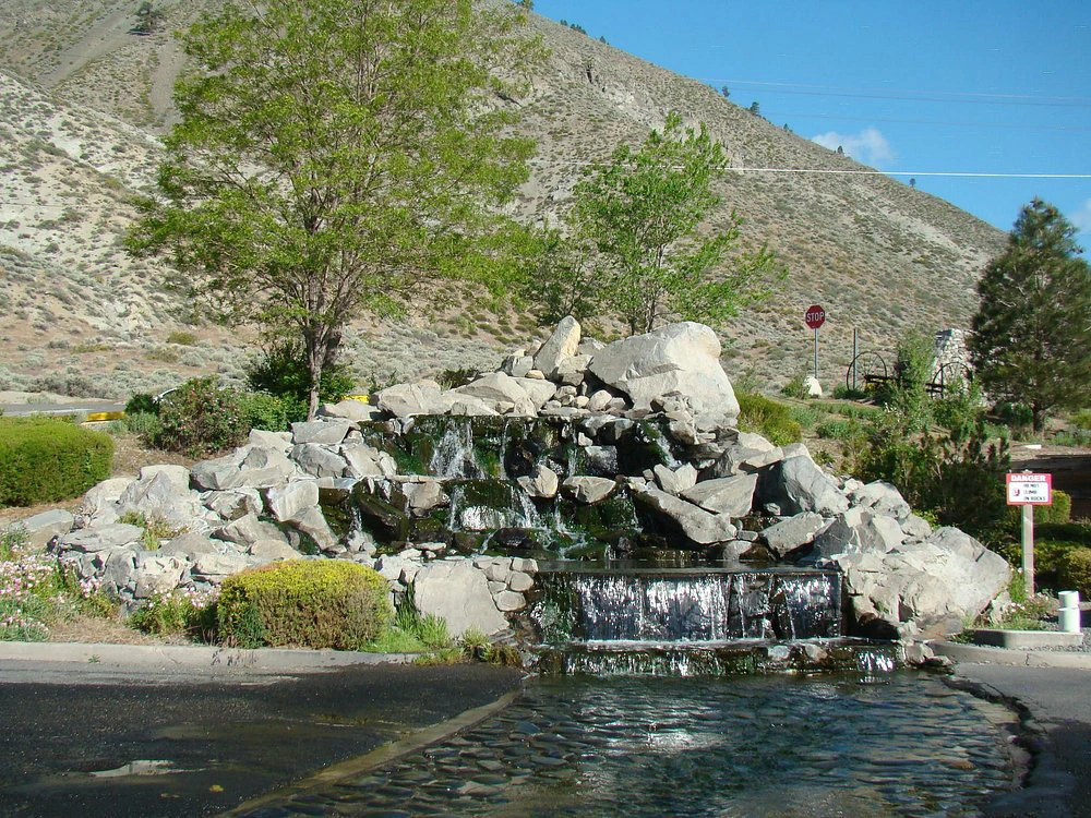 A tiered decorative rock waterfall feature located at the entrance of a resort near the mountains.