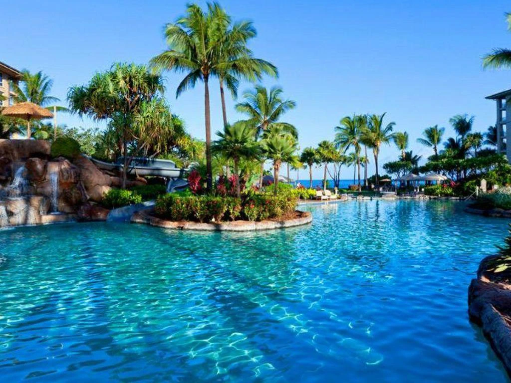 Tropical resort pool with rock waterfall and water slide, highlighting westin vacation club benefits.