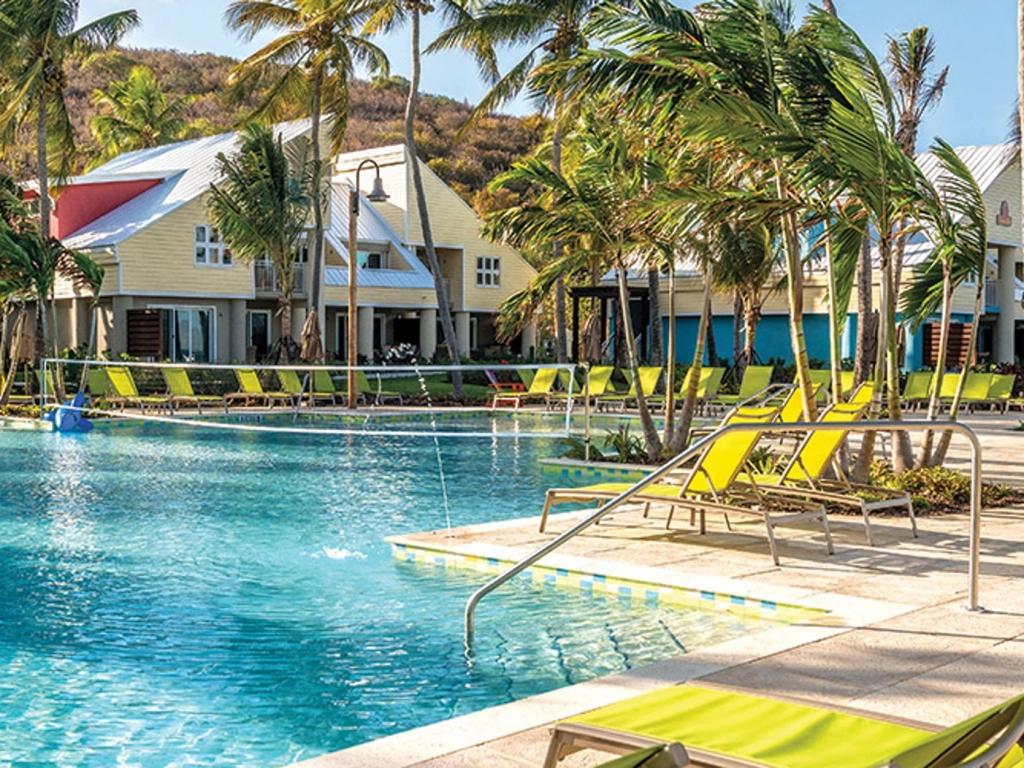 Bright yellow lounge chairs line a sparkling pool at a Margaritaville Caribbean timeshare resort in St. Thomas.