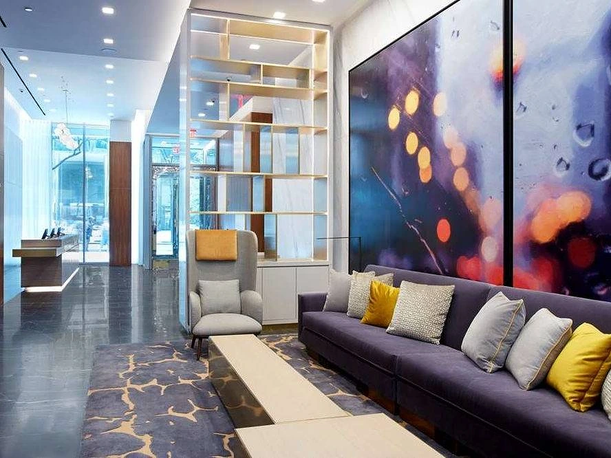 Contemporary lobby seating area with a colorful art wall at The Central at 5th by Hilton Club in New York.