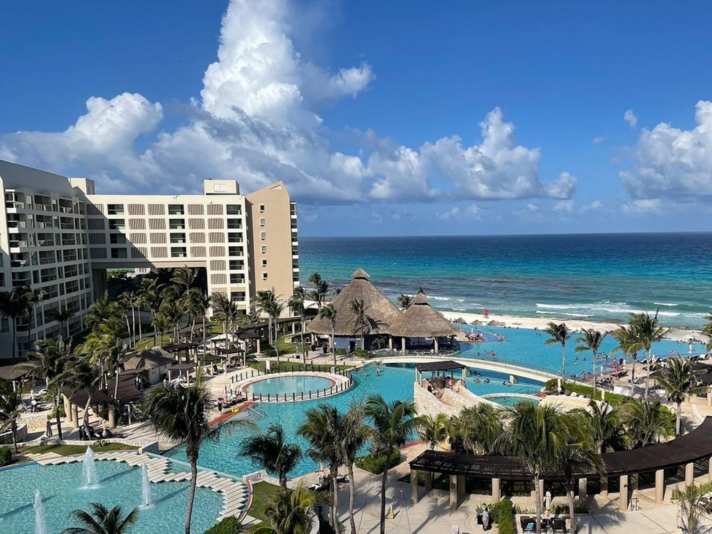 Wide view from the water of a beachfront Caribbean timeshare resort with high-rise buildings and white sand.