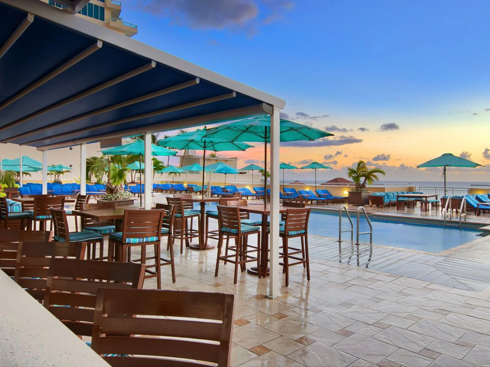 Outdoor bar and grill with high-top seating near the pool at Marriott's BeachPlace Towers at sunset.