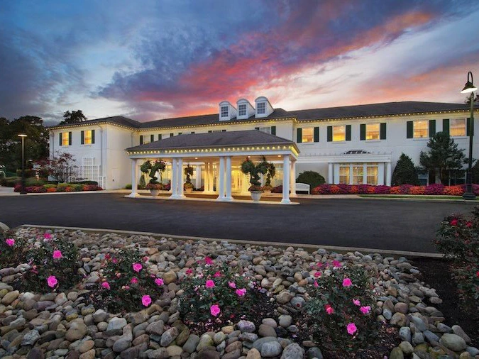 Stately white exterior of Marriott's Fairway Villas at dusk with a covered entrance and pink roses.