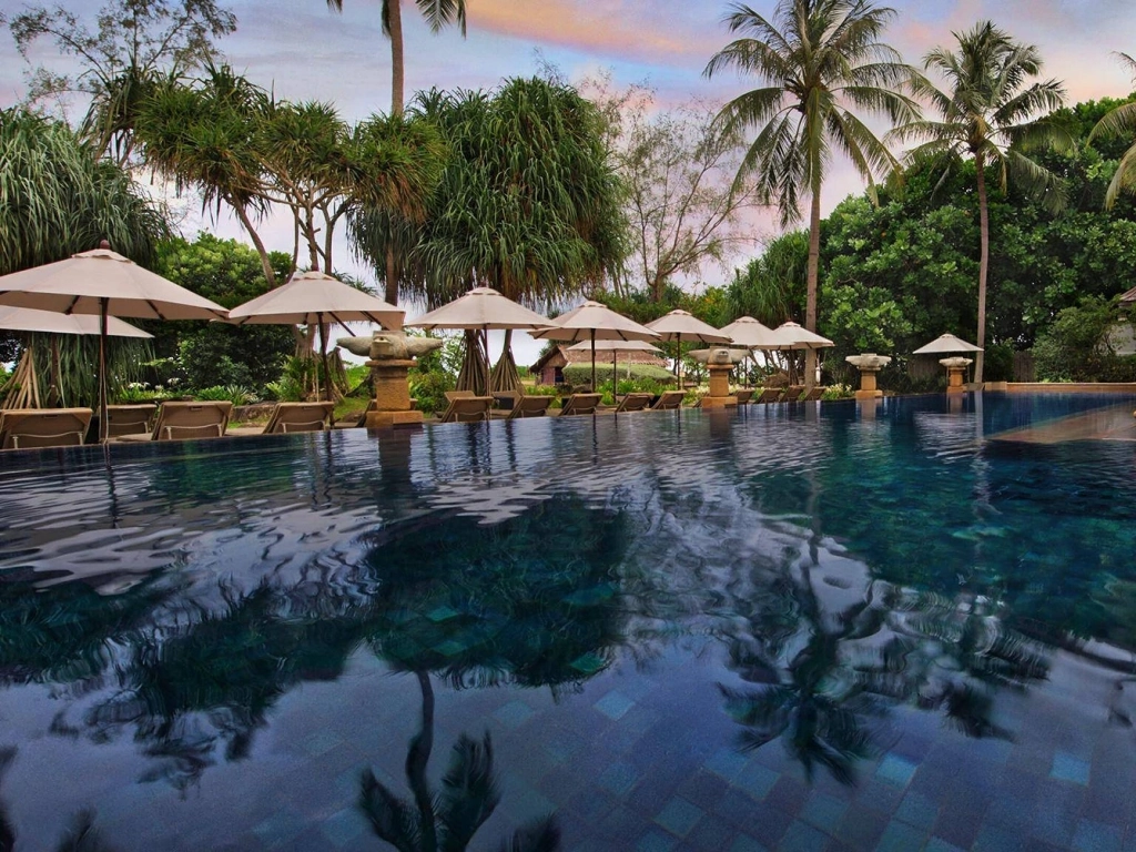 Luxury infinity pool lined with lounge chairs and palm trees at Marriott's Phuket Beach Club in Thailand.
