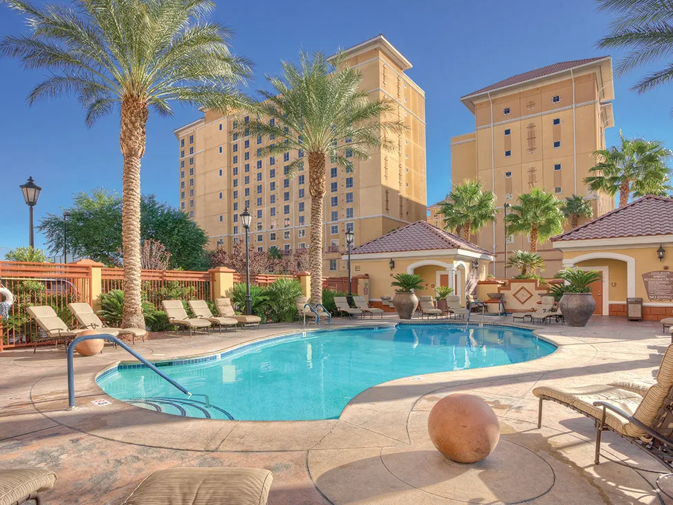 Wyndham timeshare resort pool with lounge chairs, palm trees, and hotel towers—see how much you can sell yours for.