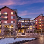 Wyndham hotel exterior at dusk in a snowy mountain setting with warm glowing windows and stone facade.